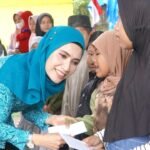 MENYERAHKAN BANTUAN (2) Ny. Uke Retno Wahyuni Faisal Hasrimy selaku Pj. Ketua TP. PKK Kabupaten Langkat Menyerahkan bantuan kepada warga