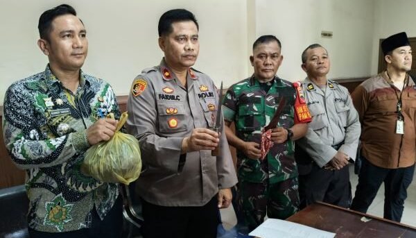 Polisi sedang menunjukkan sebilah pisau yang digunakan tersangka membunuh orangtuanya.