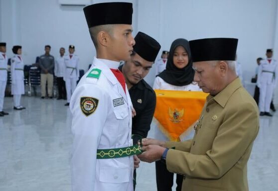 Surya memasangkan kendit kepada salah seorang  Pengibar Bendera secara simbolis.