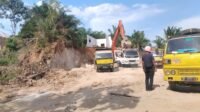 Terlihat alat berat beko secara ilegal mengisi tanah kerukan ke truk dari hasil galian C