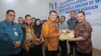 Salah seorang penerima manfaat menerima kartu BPJS Ketenagakerjaan dari Wakil Bupati Asahan Rianto.
