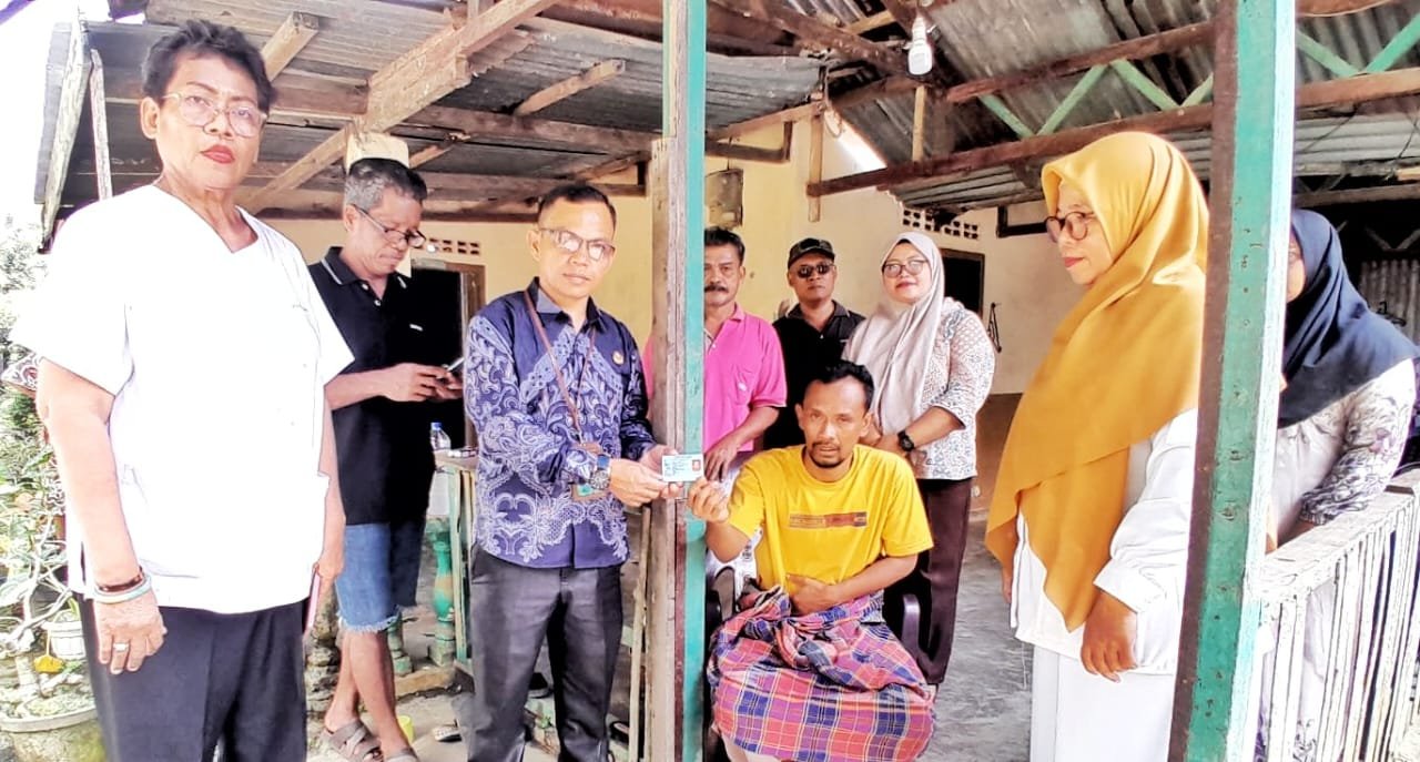 Zuang Al Chabid (kaos kuning) saat menerima e-KTP dari Disdukcapil.