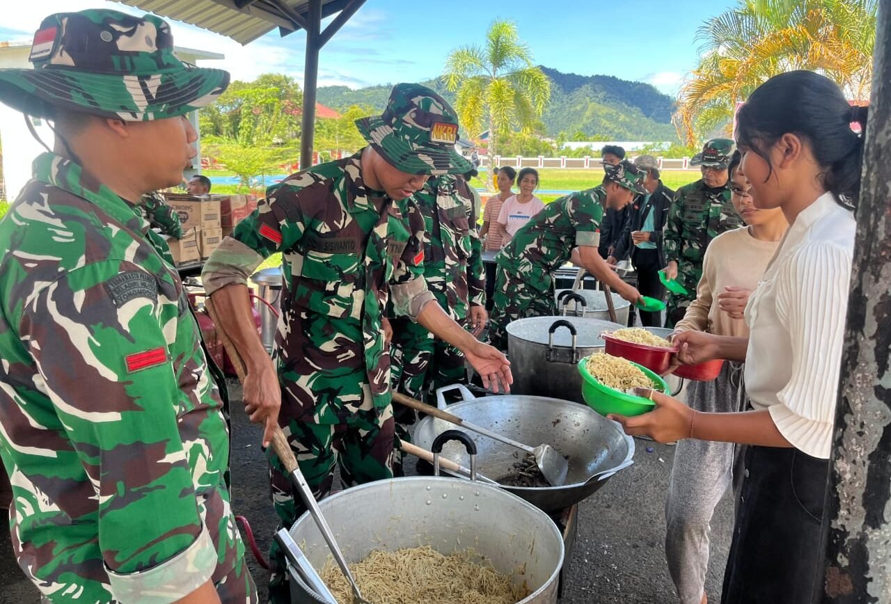 Personil TNI AD Korem 023/KS saat membagikan makanan kepada warga pengungsi di Dapur Lapangan, Selasa (2/12/2025).