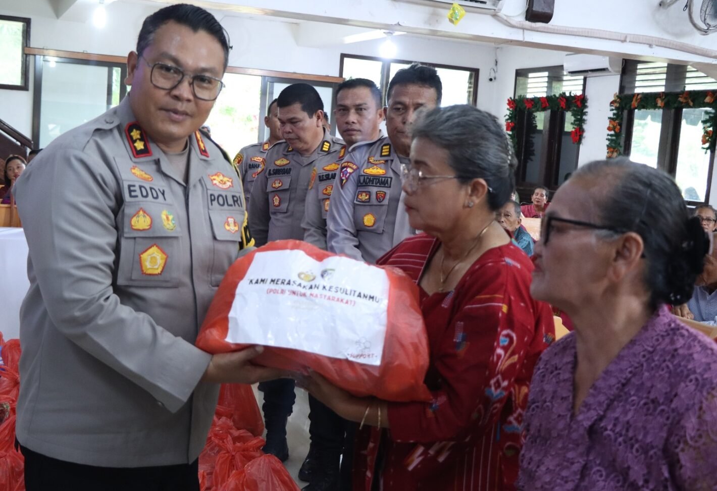 Kapolres Sibolga AKBP Eddy Inganta saat membagikan bingkisan Natal secara simbolis kepada warga Sibolga Julu yang terkena dampak bencana alam banjir dan tanah longsor , Kamis (25/12/2025).