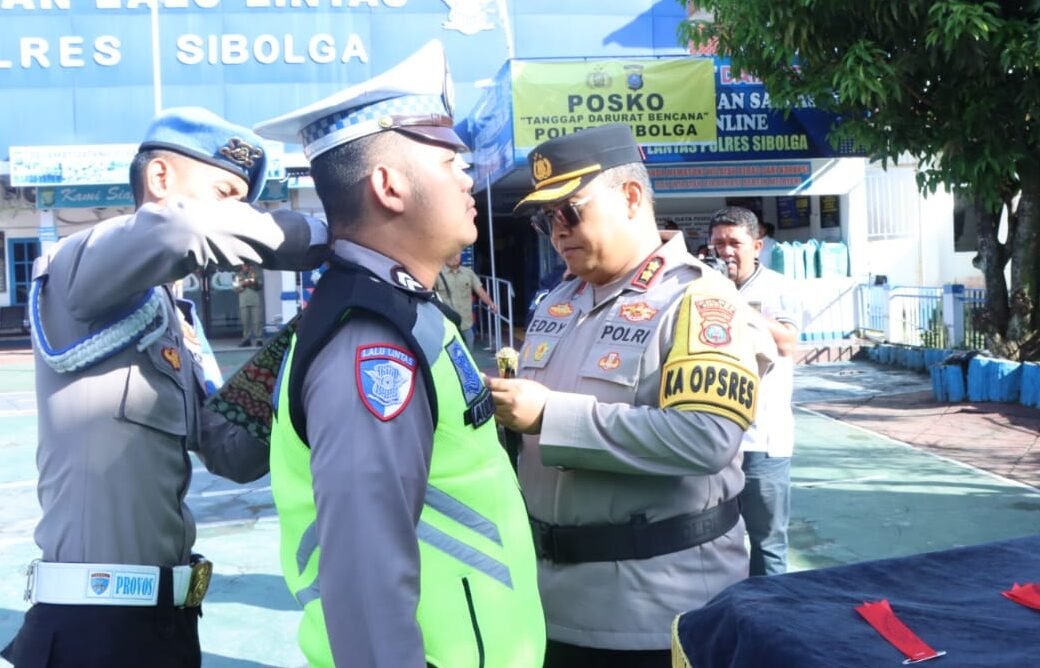 Kapolres Sibolga AKBP Eddy Inganta, S.H., S. I. K., M. H saat menyematkan pita pada personil sebagai simbol dimulainya Ops Lilin Toba 2025.