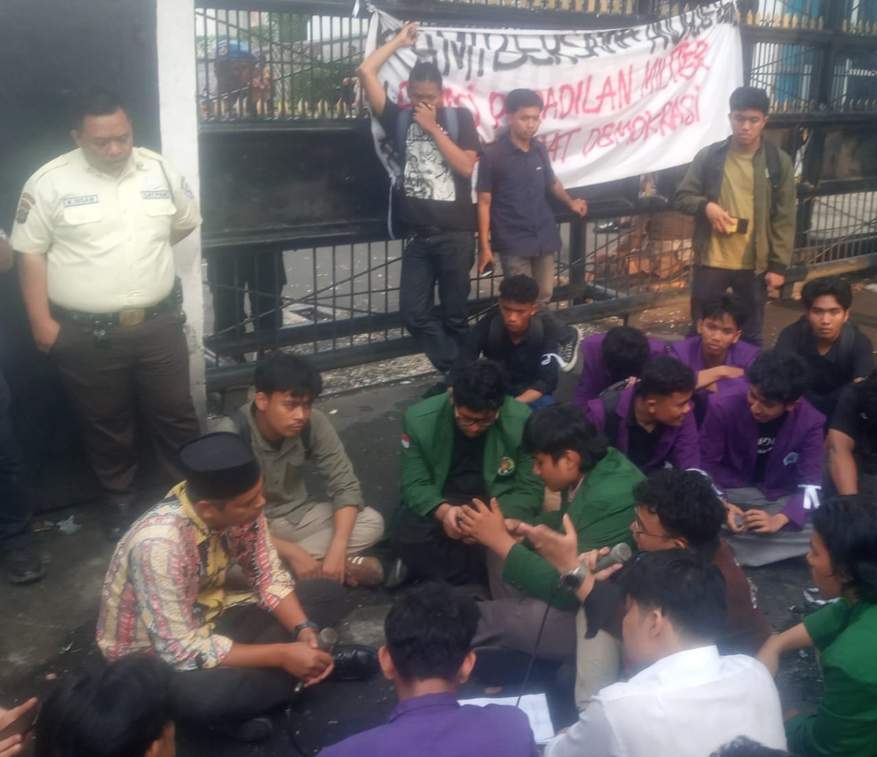 Anggota Komisi A, DPRD Sumut Gusmiyadi, SE (pakai peci) duduk di tanah di depan pintu gerbang masuk DPRD Sumut saat menerima aspirasi massa Aliansi BEM-SI Daerah Sumut. 