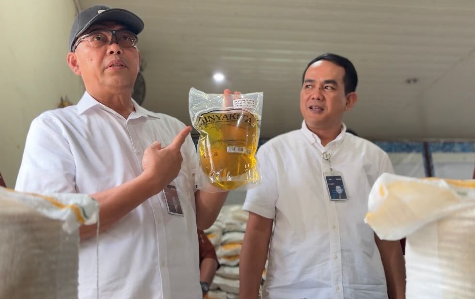 Wakil Direktur Perum Bulog Mayjen. TNI (Purn) Marga Taufiq (kiri) didampingi Pemimpin Wilayah Perum Bulog Sumut Budi Cahyanto memperlihatkan Minyakita di Kel. Pekan Labuhan, Kec. Medan Labuhan, Medan.