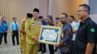 Baharuddin Siagian, Bupati Batu Bara sedang menyerahkan Piagam Penghargaan.